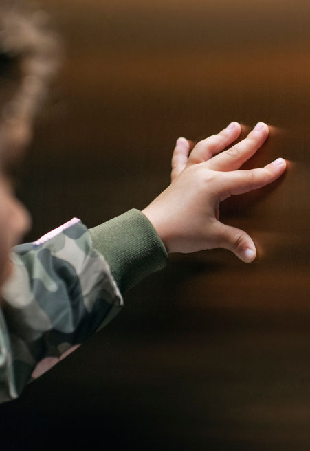 child with their hand on the elevator wall.
